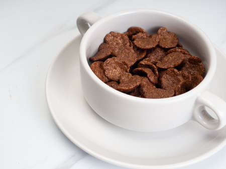 Chocolate cereal with milk on a white bowl, placed on a white marble tableの写真素材