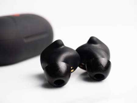 A pair of black wireless earphone with case on a white isolated background
