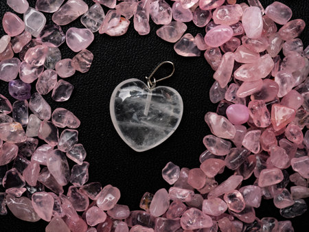White transparent cryatal heart shaped pendant surrounded by pink gemstones on a black backgroundの写真素材