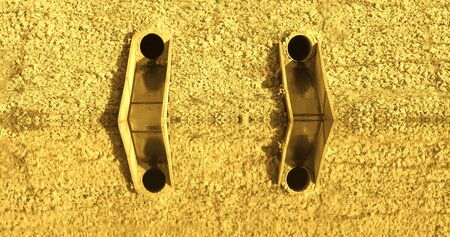 Close up outdoor view of a two symmetric metallic gutters on the stone wall with a reflections in...