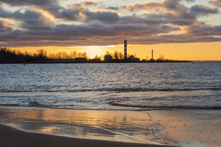 View to the Daugavgriva lighthouse from Mangalsala pier against colorful sunset skyの写真素材