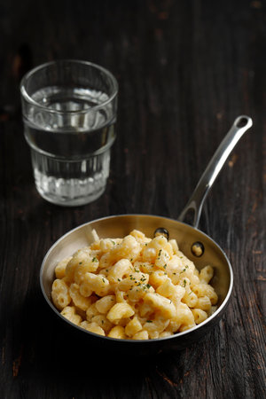Mac and Cheese, American Style Macaroni Pasta with Cheesy Creamy Sauce and Crunchy breadcrumbs Topping on Dark Rustic Tableの写真素材