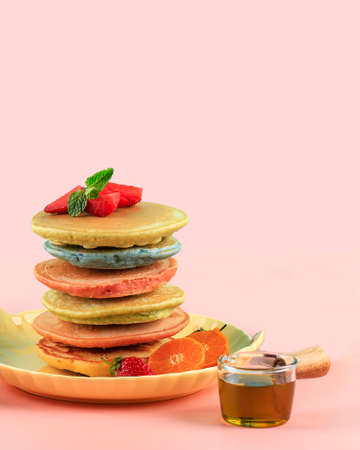 Colorful Pancakes Stack with Maple Syrup and Strawberry isolated on a pink background. Family Breakfast. Brunch. Shrove Tuesday. Mardi Gras. Snacks. Sweets. Food. Dessert.の写真素材