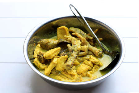 Opor Ayam Ceker, Indonesian Yellow Curry Traditional Food in a Bowl. Opor Made from Chicken Cooked with Coconut Milk and Spices. Served to Celebrate Eid Adha and Eid Fitr. Selective Focus.の写真素材