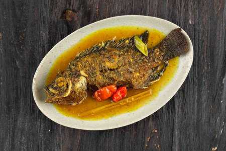 Pesmol Ika Nila, Tilapia Yellow Curry, Popular Curry Recipe made from Fried Fish in West Java,...