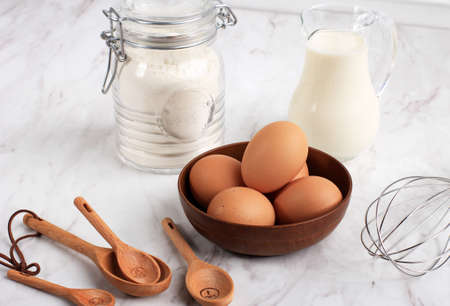 Eggs, Flour, Milk, Sugar, Measuring Spoon,  and Wire Whisk. Preparation for Baking