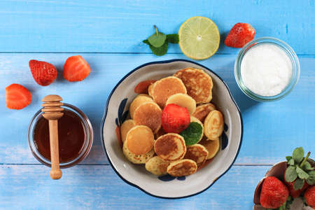 Mini Pancakes with Fresh Strawberries  and Maple Syrup, on Wooden Tableの写真素材