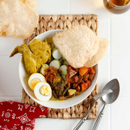 Lontong Cap Go Meh. Indonesia Peranakan Dish of Rice Cake Soup or Lontong Sayur with Opor Ayam Chicken Curry, Spicy Chayote Curry, SAmbel Goreng Ati Kentang, and Egg. Served with Shrimp Crackerの写真素材