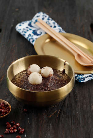 Korean Dongji Red Bean Porridge with Rice Cake, on Wooden Table