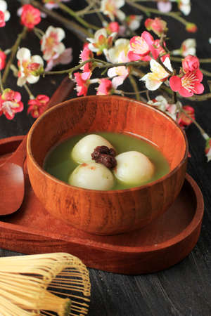 Matcha Tangyuan (Tang Yuan) with Sweet Matcha Soup in Wooden Bowl on Black Wooden Table Background...