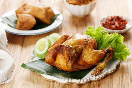 Deep Fried Whole Fried Chicken, Served with Cucumber, vegetable, and Sambal. Indonesian Popular Side DIsh or Bakakak Hayamの写真素材