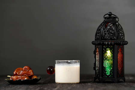 Ramadan concept. Fasting. Dates, Milk Dates Susu Kurma, and Ramazan Lantern on a wooden table with Grey Dark wall background.の写真素材