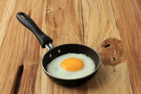 SUnny Side Up Egg on Mini Pan on Wooden Tableの写真素材