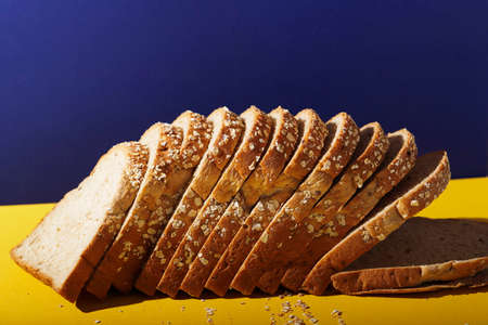 Close Up Whole Grain Bread with Oat Flakes and Seeds on Blue and Yellow Pop Color, Copy Space for Textの写真素材