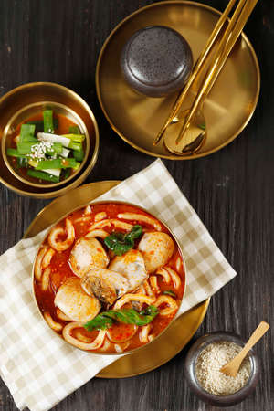 Jjampong Korean Spicy Noodle Soup on Golden Metal Bowl, Served with Green Onion Kimchi. Top View on...