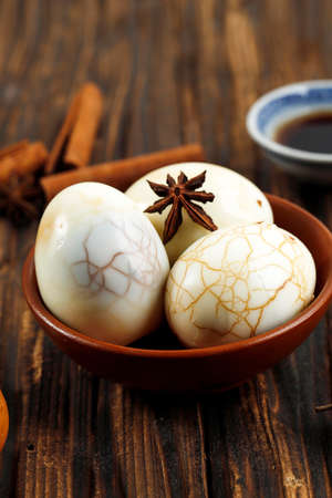 Traditional Chinese Tea Eggs Served on Ceramic Bowl. Perfect Appetizer for Chinese Dinner for Asian Themed Easter Picnic. On WOoden Tableの写真素材