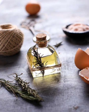 A Small Bottle of Olive Oil with herbs above Rustic Table. Ready to Cook