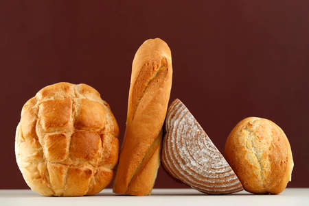 Various Rustic Bread, Sourdough, Baguette, Boule Isolated on Brown Table. Copy Space for Text or...