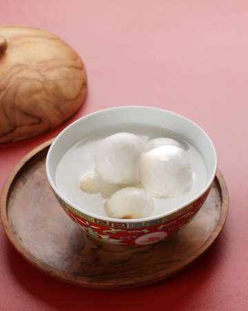 Tang Yuan, Chinese Glutinous Rice Dumpling Balls with Sugar Ginger or Palm Sugar Syrup on Red Chinese on Black Background for Winter Solstice New Year Festival Food.の写真素材