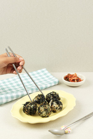 Female Hand Holding Chpstick, Eat Jumeokbap Korean Seaweed Rice Ball with Kimchi