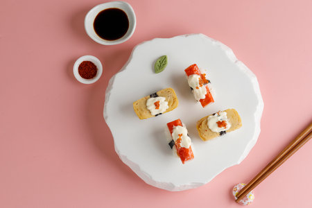 Tamago and Crabstick Roll Sushi on White Oriental Plate, Pink Background. Copy Space for Textの写真素材
