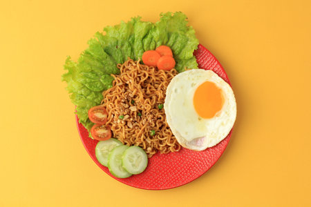 Top View Indomie Goreng. Indonesian Instant Noodle with Sunny Side Egg, on Yellow Tableの写真素材