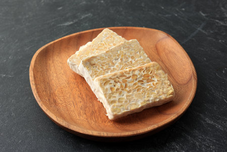 Sliced Raw Tempe or Tempeh on Wooden Plate. Tempeh is Superfoods, Meat Alternative, Protein Sources,...