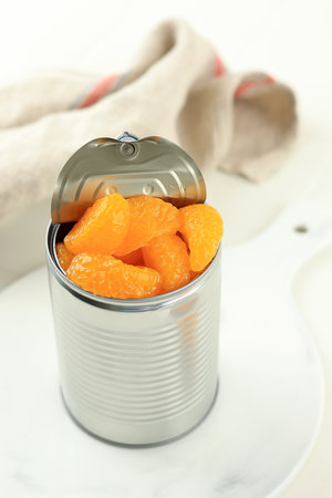 Canned Orange Tangerine in Swwt Syrup. Pickled Preserved Mandarin Fruit in the Can on White Table.の写真素材