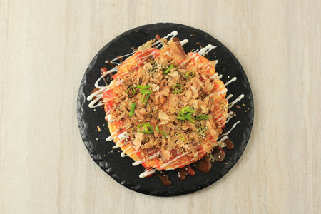 Top View Japanese Savory Egg Pancake Okonomiyaki on Black Slate Plateの写真素材