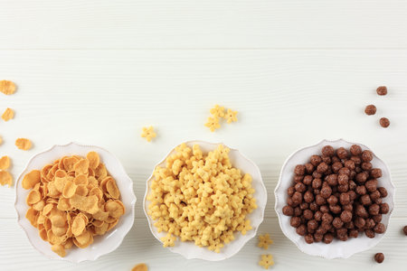 Top View Three Various Cereal Breakfast on White Bowl, Chocolate Balls, Corn Flakes, and Honey Star....
