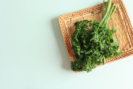 Top View Fresh Aromatic Parsley on  Rattan Plate, Copy Space on Green Mint Table Background with Copy Space for Textの写真素材
