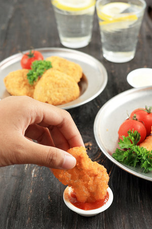 Female Hand Dipping Crispy Nugget on Spicy Sauceの写真素材