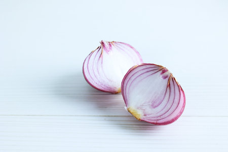 Peeled and Halved Red Onion on a White Wood Table: Two Pieces of Peeled Purple Onion Isolated on Whiteの写真素材