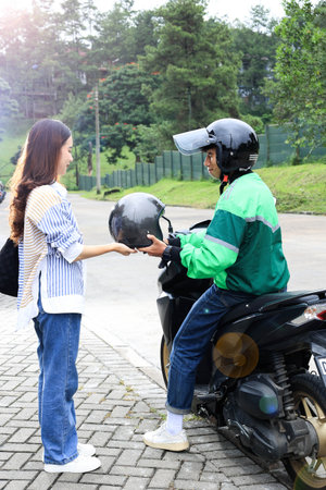 Female Customer Order Online Transportion in the Morning to the Office, Driver Giving Helmet to Passengerの写真素材