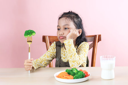 Asian Little Cute Girl Refuses to Eat Broccoli Healthy Vegetables. Picky Eater Kids Conceptの写真素材