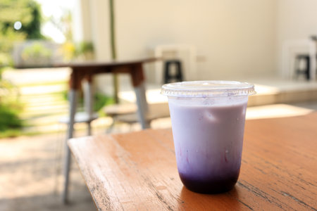 Iced Taro Latte on Plastic to go Cup, Above Wooden Table. Cafe Menu Takeaway Conceptの写真素材
