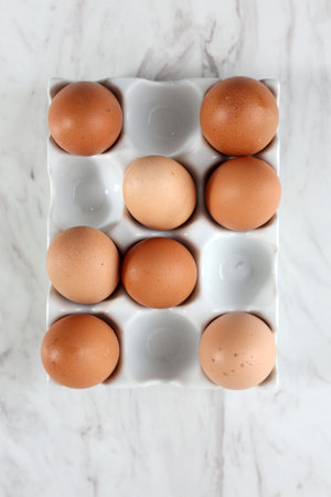 Top View Eggs on Ceramic Egg Tray, Isolated on White Marble Table