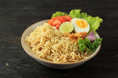 Indomie Rebus or Instant Boiled Noodle with Boiled Egg, Tomato, and Sliced Lime.の写真素材