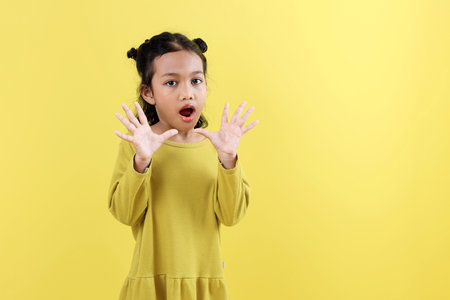 Cute Little Asian  Kids with Shocked Surprise Face, Isolated on Yellow Backgroundの写真素材