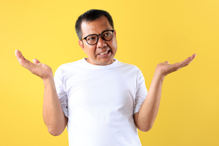 Middle Age Asian man using White T Shirt with Shrug Expression, Raising Both Shoulders. I don't Care Conceptの写真素材