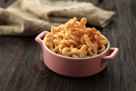 Lanting, Crispy Traditional Javanese Snack made from Cassava Flour, Savory and Garlic Flavor. Shaped Eight Number,  Served on Pink Bowlの写真素材