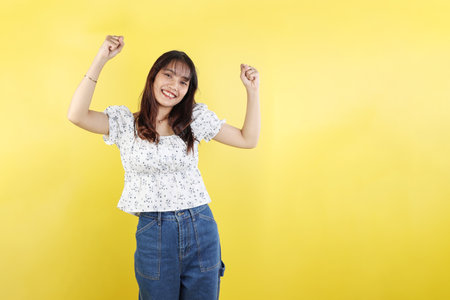 Young Smiling Happy Positive Cool Woman Wearing Casual Clothes Raise Up Hands Dance Have Fun. Isolated on Yellow Background studio portrait. Asian Lifestyle Conceptの写真素材