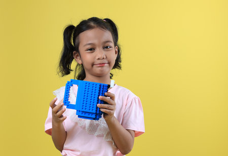 Asian Girl Kids Holding Blue Cup, Isolated on Yellow Backgroundの写真素材
