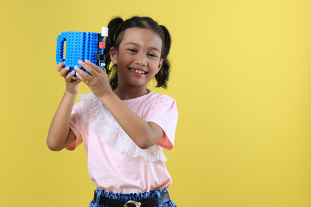 Asian Girl Kids Drink Water or Milk  from Blue Cute Cup, Isolated on Yellow Backgroundの写真素材