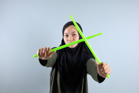 Female Muslim doing Poundfit Rockstar Workout with Green Stick, Isolated on Grey Backgroundの写真素材