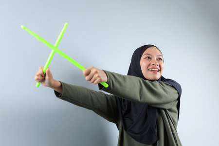 A Hijabi Woman  doing Pound Fit Workout with Green Stick, Isolated on Grey Background. Close Up, Low Angleの写真素材