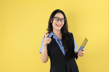 Portrait of Young Asian Woman, Company Worker in Glasses, Smiling and Holding Digital Tablet Computer, Standing Over Yellow Backgroundの写真素材