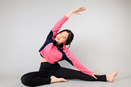 Young Asian Yoga Female Stretching Her Hand, Isolated on Grey Backgroundの写真素材