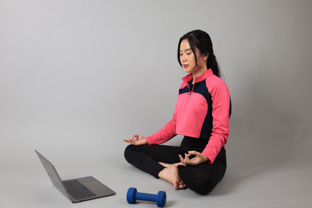 Young Woman Practicing Yoga with Online Lessons in Laptop at Home. Yoga at Home, Online Learningの写真素材