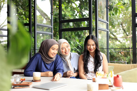 Group of Cheerful and Pretty Asian Female Friends are Enjoying Eating food, Drinking, and Hanging Out at a Restaurant or Cafe with Green Plant Outdoorの写真素材